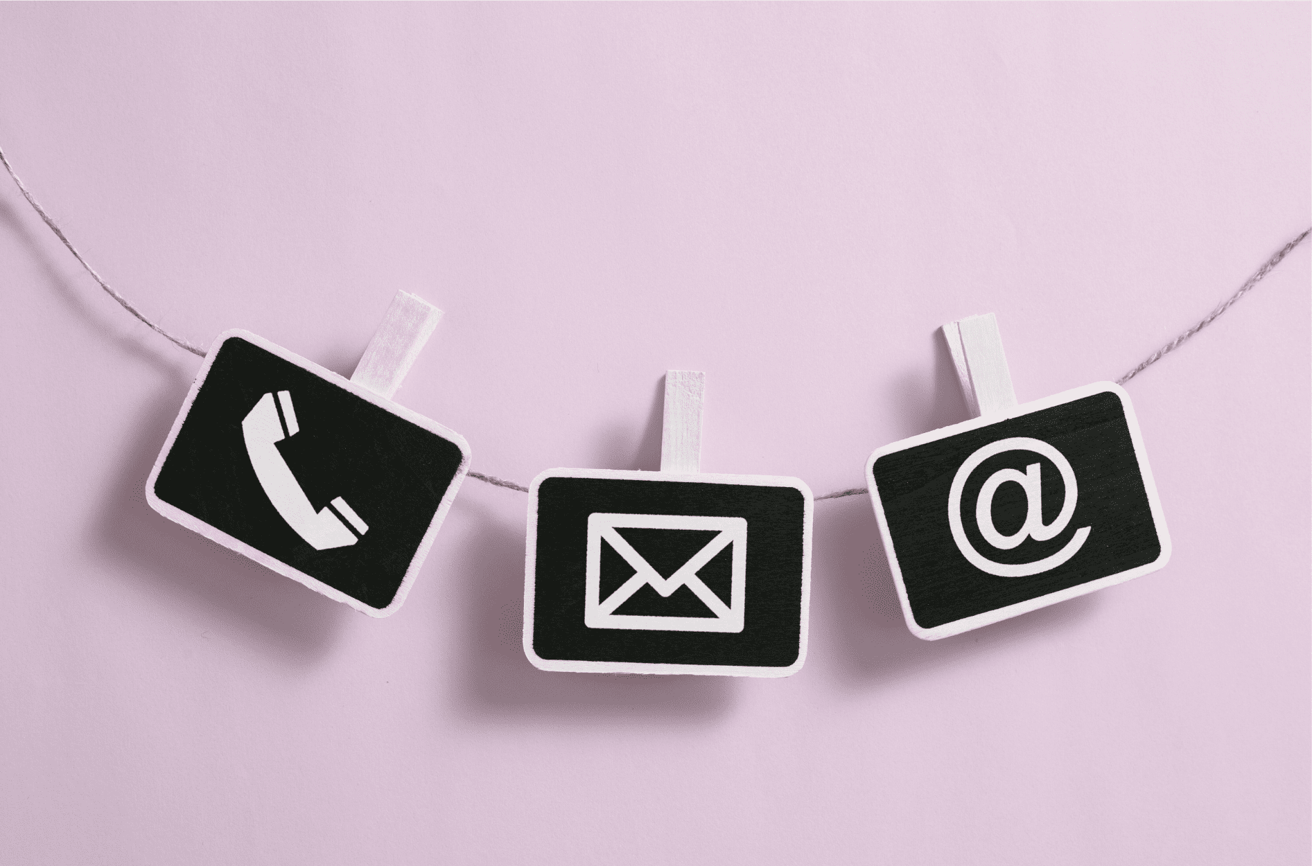 A piece of rope with three cards clipped to it. One card shows a telephone symbol, another an email symbol, and the third is an at sign.
