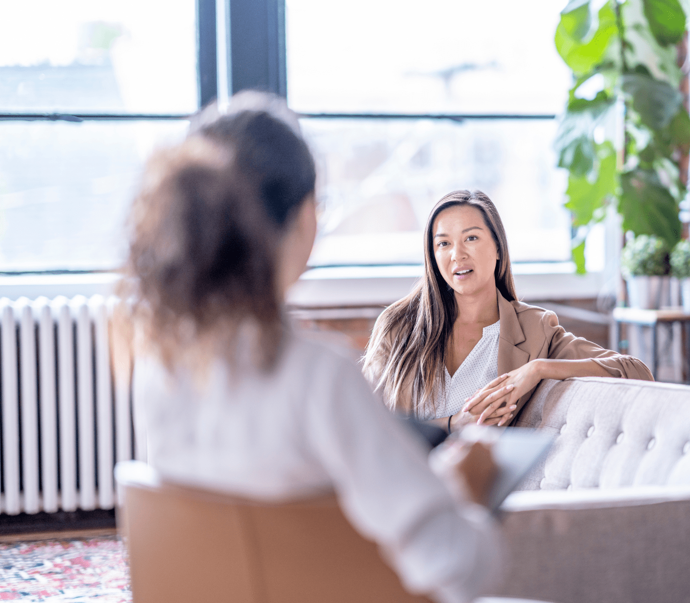 Two women sat on separate sofas engaging in a conversation