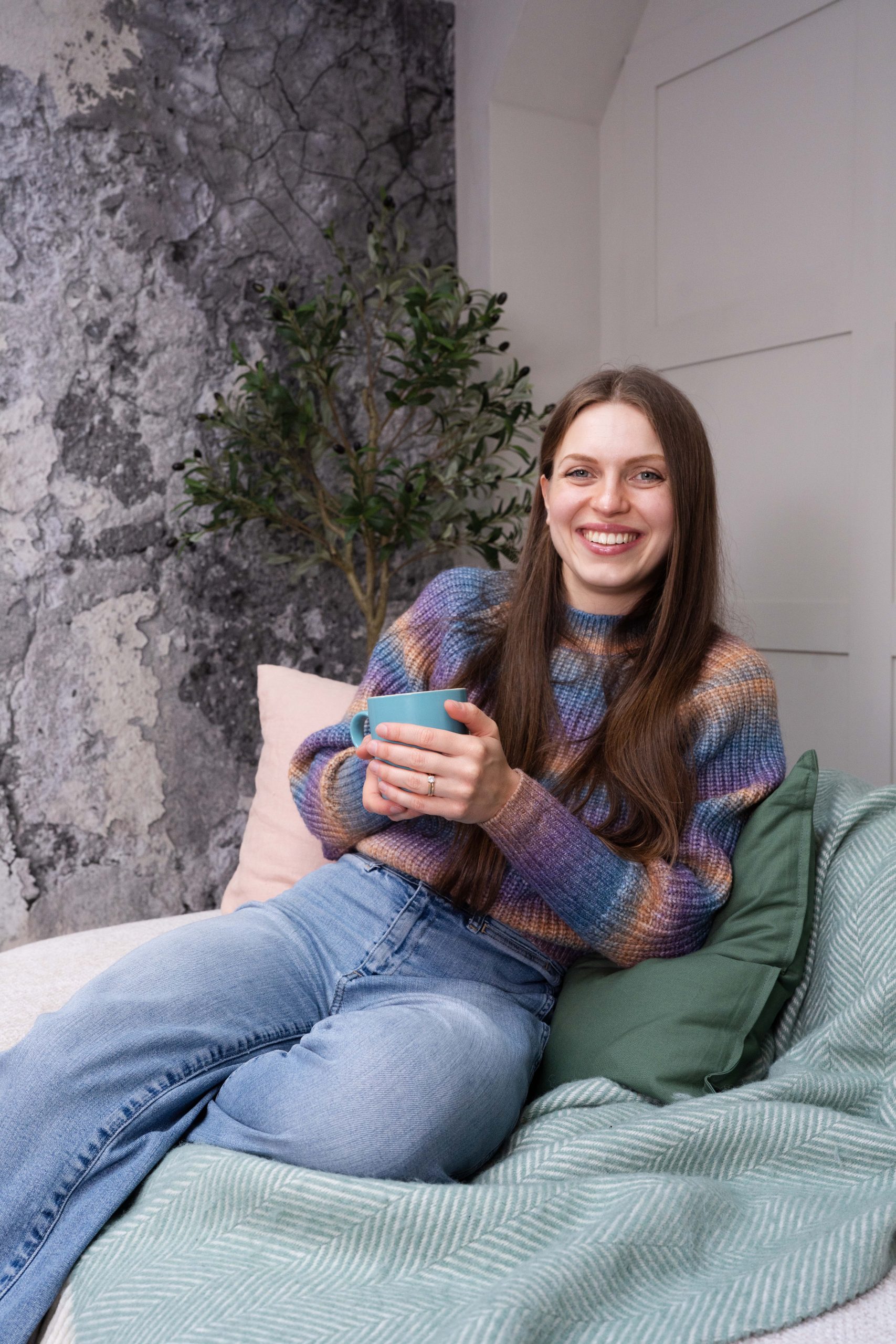 Megan sat on the sofa smiling with a cup of tea