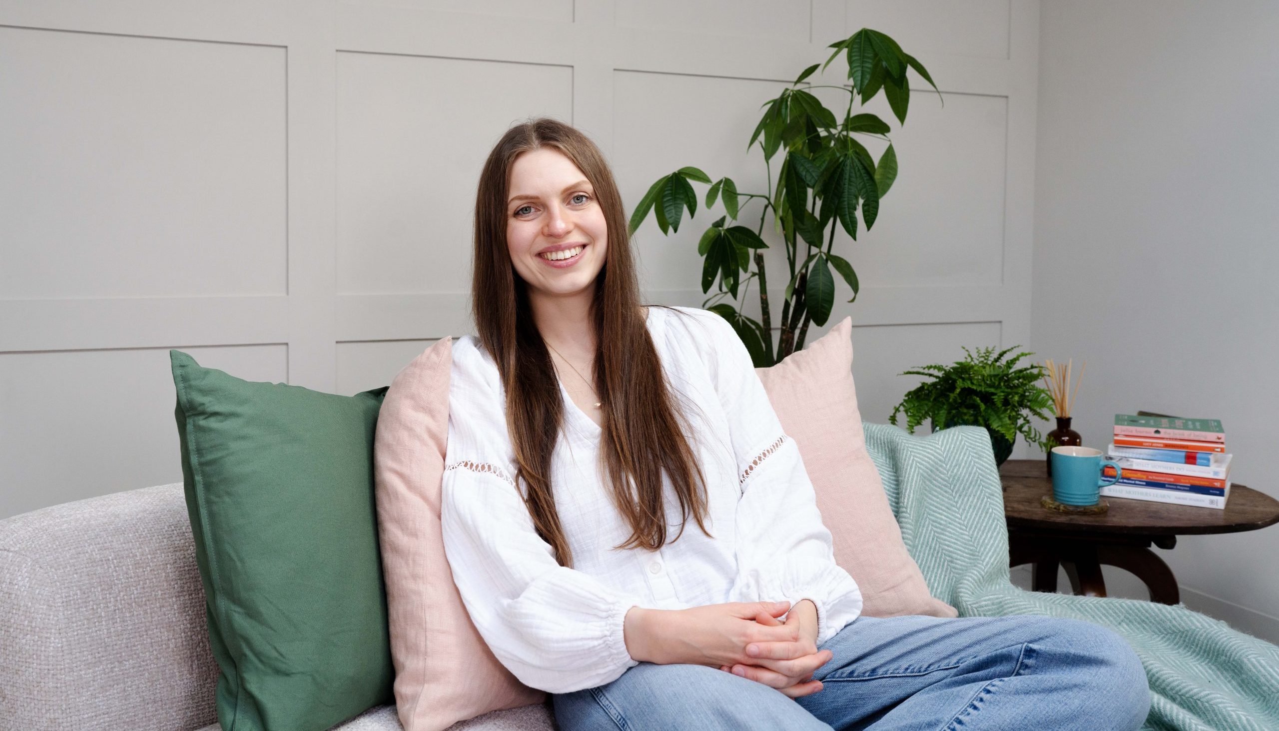 Megan sat on a sofa in a white top and jeans